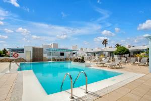 - une piscine dans un complexe avec des chaises longues dans l'établissement Mar Azul Corralejo- Adults Only, à Corralejo