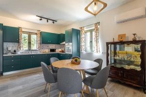 une cuisine avec des armoires vertes, une table et des chaises dans l'établissement Mani Harmony Stone House, à Agios Nikolaos