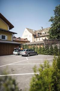 dois carros estacionados num parque de estacionamento ao lado de um edifício em Emma Historic Hotel em Villabassa