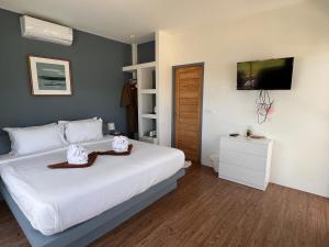 um quarto com uma cama branca e uma televisão na parede em Pearl of Samui Resort em Lamai