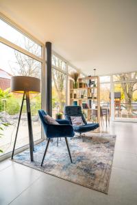 een woonkamer met 2 stoelen en een lamp bij A16 Design Panzió in Harkány