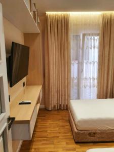 - une chambre avec un lit et une télévision dans l'établissement Olives Residence, à Dhërmi