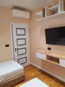 Cette chambre comprend un lit, une télévision et une porte. dans l'établissement Olives Residence, à Dhërmi