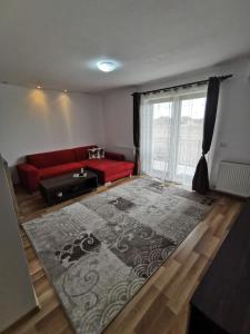 een woonkamer met een rode bank en een groot tapijt bij Apartament Ovidiu in Giroc