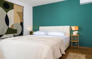 a bedroom with a white bed with a blue wall at Rivus Apartments in Omiš