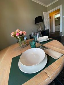 a wooden table with plates and glasses and flowers on it at Zentraler Altbaucharme mit Blick über die Stadt in Kiel