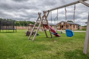 einen Spielplatz mit Rutsche und Schaukeln im Hof in der Unterkunft Osada Trzy Siostry in Pobierowo