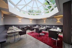 a dining room with tables and chairs and a large skylight at Hotel Akazienhaus in Herzogenaurach