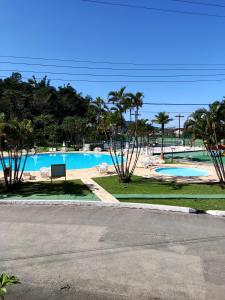 Apartamento até 10 pessoas na enseada Guarujá em condomínio clube praia piscinas salão jogos quadra futebol campo parquinho brinquedos Wi-fi Home office في غوارويا: حمام سباحة مع مقاعد و نخيل