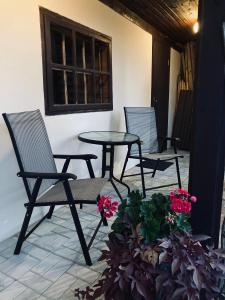 3 sillas y una mesa en un patio con flores en Lotes apartamenti, en Kuldīga