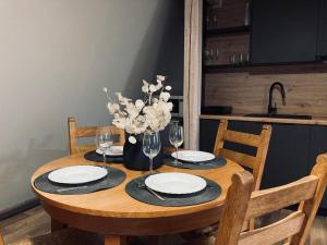 una mesa de madera con gafas y un jarrón de flores en Lotes apartamenti, en Kuldīga