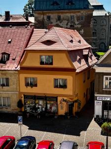 un edificio giallo con tetto rosso accanto alle auto parcheggiate di Dům V Centru a Česká Kamenice