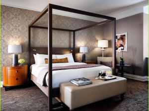 a bedroom with a canopy bed and a ottoman with a table at Fairmont Palliser in Calgary