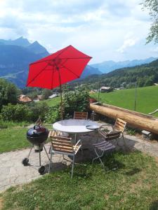 een tafel en stoelen met een rode parasol en een grill bij Breitmoos in Hasliberg