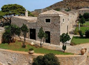 un bâtiment en pierre avec des arbres devant lui dans l'établissement Lazareto Hotel, à Monemvasia