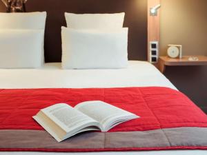 - un livre ouvert sur un lit avec une couverture rouge dans l'établissement Mercure Vienne Sud Chanas, à Chanas