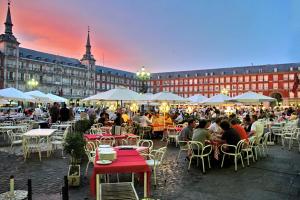 eine Gruppe von Personen, die vor einem Gebäude an Tischen sitzen in der Unterkunft Woohoo Rooms Boutique Sol in Madrid