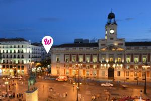 ein großes Gebäude mit einem Uhrturm darüber in der Unterkunft Woohoo Rooms Boutique Sol in Madrid