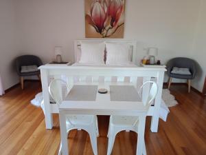 - une table et des chaises blanches dans une chambre avec un lit dans l'établissement Kincumber House, à Kincumber