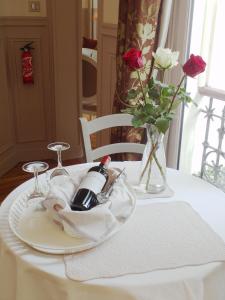 a table with a plate with a bottle of wine and roses at Chambre d hôte : Louvre Elegant Apt Suite in Paris