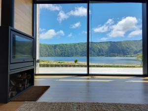 een woonkamer met een groot raam met uitzicht op een meer bij Sete Cidades Lake Cabin - Casa da Lagoa in Ponta Delgada