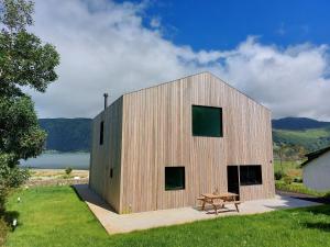 een houten huis met een picknicktafel ervoor bij Sete Cidades Lake Cabin - Casa da Lagoa in Ponta Delgada