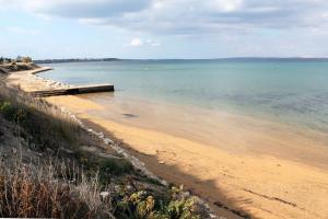 een strand met een houten pier in het water bij Apartments and rooms by the sea Nin, Zadar - 5858 in Nin