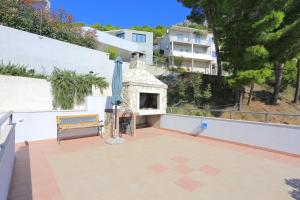 une terrasse avec une cheminée, un parasol et un banc dans l'établissement Apartments by the sea Brela, Makarska - 6688, à Brela