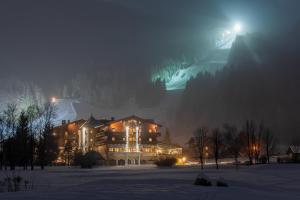 un grande edificio nella neve di notte di Hotel Zum Jungen Römer a Radstadt