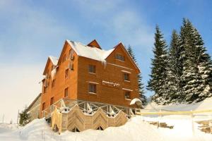 een groot houten gebouw is bedekt met sneeuw bij Smerichka Hotel in Dragobrat