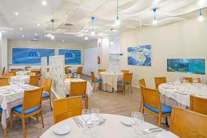 une salle à manger avec des tables et des chaises blanches dans l'établissement Peñiscola Plaza Suites, à Peñíscola