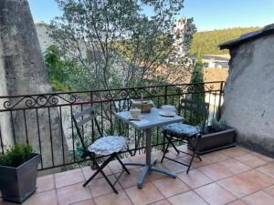 einen Tisch und Stühle auf dem Balkon in der Unterkunft Charmante chambre dans belle Maison typique du Village in Lagorce