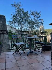 eine Terrasse mit einem Tisch und Stühlen auf dem Balkon in der Unterkunft Charmante chambre dans belle Maison typique du Village in Lagorce