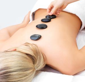 a woman laying on her back with spa stones on her back at Hotel Akazienhaus in Herzogenaurach