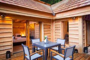 een patio met een tafel en stoelen en een slaapkamer bij Les Lodges de Babylone in Larringes