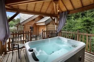 een hot tub op het dek van een blokhut bij Les Lodges de Babylone in Larringes