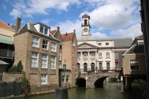 een gebouw met een klokkentoren en een brug over een rivier bij B&B verDRAAId fijn in Dordrecht