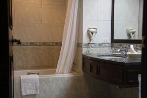 La salle de bains est pourvue d'un lavabo, d'une baignoire et d'un miroir. dans l'établissement Herald Suites Solana, à Manille