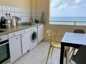 een keuken met een tafel en een wasmachine bij L’Appart - Les pieds dans l’eau in Sainte-Luce