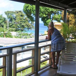 Una mujer parada en un balcón con vistas al océano en La Casa de Castara, en Castara