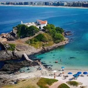 eine Gruppe von Menschen am Strand im Wasser in der Unterkunft ** SUITE PRIVATIVA PRAIA DO FORTE CABO FRIO ** in Cabo Frio