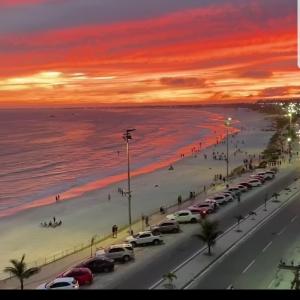 eine Stadtstraße mit Autos am Strand bei Sonnenuntergang in der Unterkunft ** SUITE PRIVATIVA PRAIA DO FORTE CABO FRIO ** in Cabo Frio