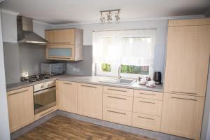 una cucina con armadi in legno, lavandino e finestra di Apartament Lazur a Piła