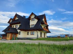 una casa con un tetto nero in cima a un campo di Willa u Polczyków a Białka