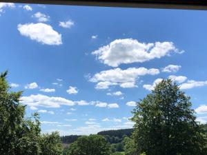 un cielo azzurro con nuvole bianche e alberi di Le refuge de Kila a Waimes