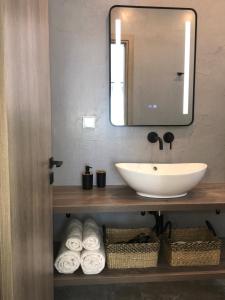 bagno con lavandino, specchio e asciugamani di ANASTASIA LUXURY SUITES 2 a Tolo