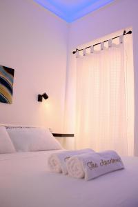 a white bedroom with a bed with two towels on it at The Apartment in Porto Santo Stefano