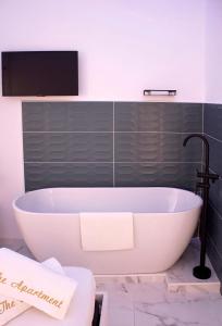 a bath tub in a bathroom with a tv on the wall at The Apartment in Porto Santo Stefano