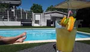 una bebida sentada en una mesa junto a una piscina en Hôtel Restaurant Le Clos Charmant, en Vallon-Pont-dʼArc