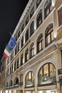 un bâtiment avec deux drapeaux sur son côté dans l'établissement Hotel Firenze, à Venise